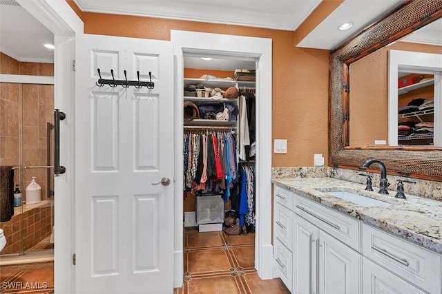 full bathroom featuring tile patterned flooring, vanity, ornamental molding, a shower stall, and a walk in closet