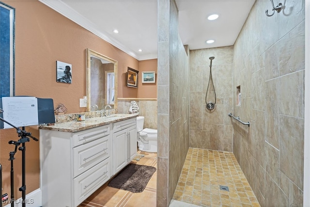 bathroom featuring crown molding, tile walls, toilet, a tile shower, and vanity