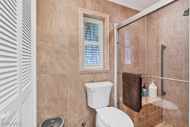 full bathroom featuring toilet, a shower stall, and tile walls