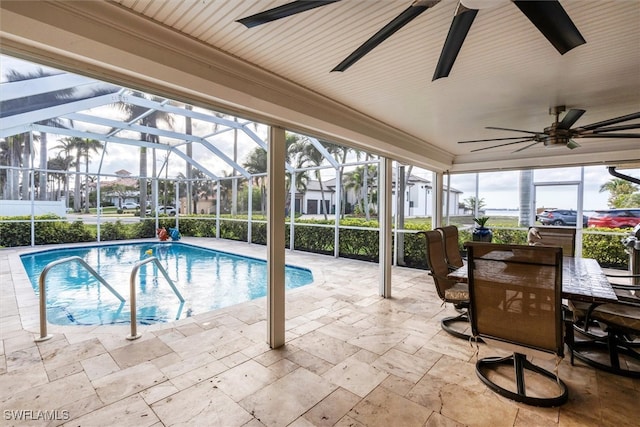 outdoor pool with a patio, glass enclosure, and a ceiling fan