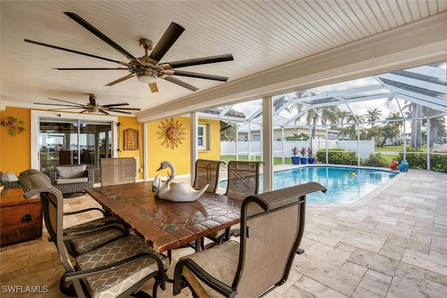 exterior space featuring a patio, a lanai, fence, a ceiling fan, and a fenced in pool