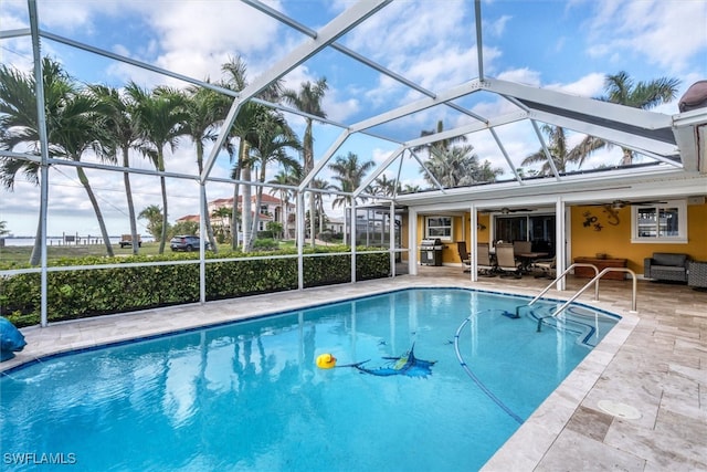 outdoor pool with ceiling fan, a lanai, an outdoor hangout area, area for grilling, and a patio area