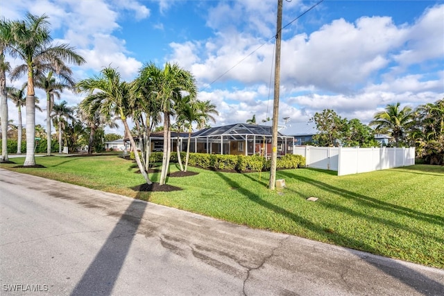 exterior space featuring a front yard, glass enclosure, and fence