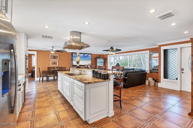 kitchen with a breakfast bar, stainless steel refrigerator with ice dispenser, island exhaust hood, and visible vents