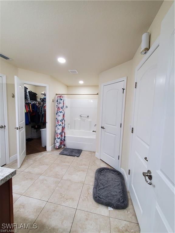 bathroom featuring shower / tub combo, visible vents, tile patterned floors, a walk in closet, and vanity