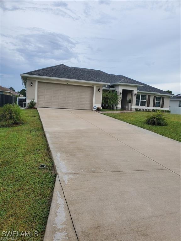 view of front of property featuring driveway, stucco siding, a garage, and a front yard