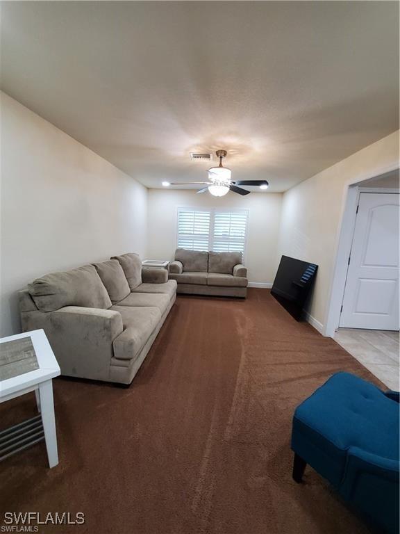 living area featuring a ceiling fan, carpet, visible vents, and baseboards