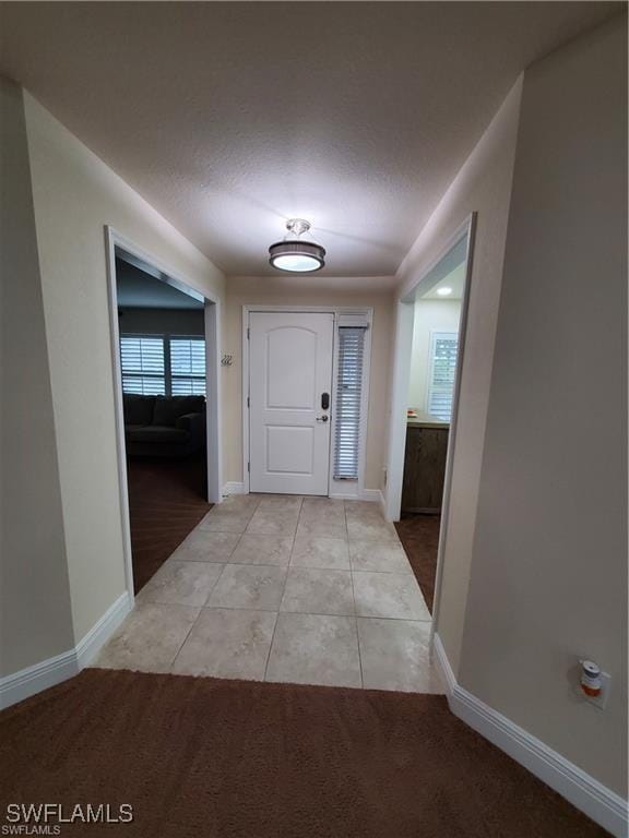 interior space featuring light carpet, baseboards, and light tile patterned floors