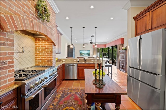 kitchen featuring a peninsula, appliances with stainless steel finishes, light stone counters, and hanging light fixtures