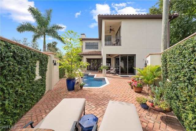 rear view of house with an outdoor pool, a ceiling fan, a patio, a balcony, and stucco siding