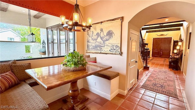 dining room with arched walkways, breakfast area, baseboards, and an inviting chandelier