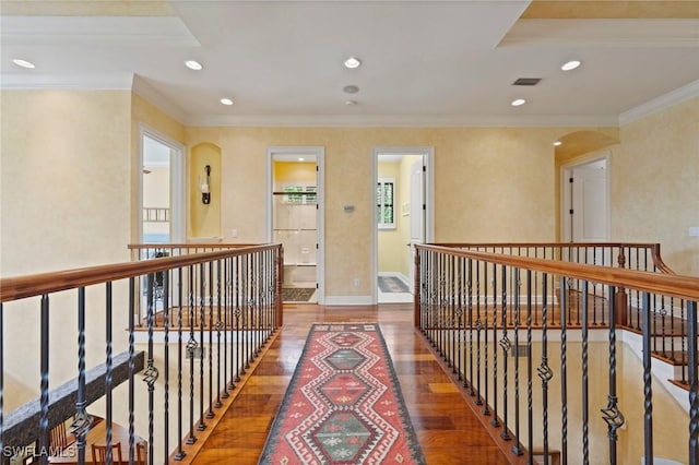 corridor featuring arched walkways, crown molding, recessed lighting, visible vents, and wood finished floors