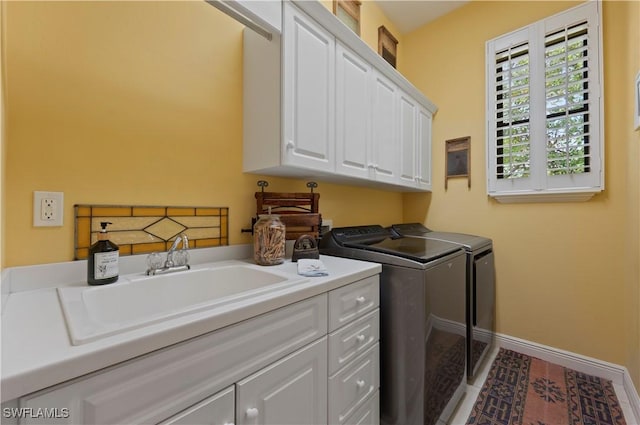 clothes washing area with cabinet space, baseboards, washer and dryer, and a sink