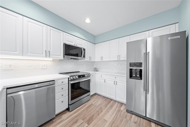 kitchen with stainless steel appliances, tasteful backsplash, light countertops, and white cabinets