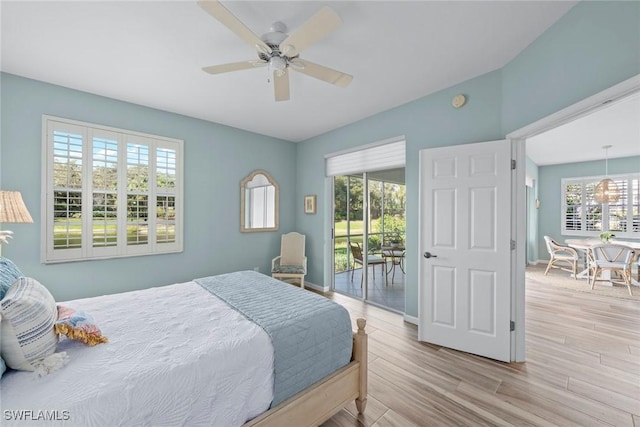 bedroom with baseboards, multiple windows, wood finished floors, and access to exterior