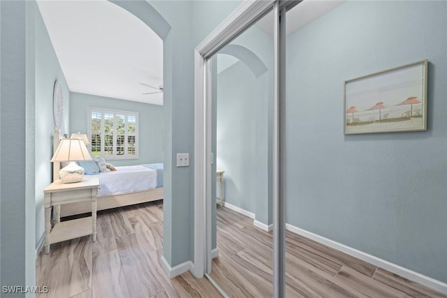 bedroom featuring baseboards, arched walkways, and wood finished floors