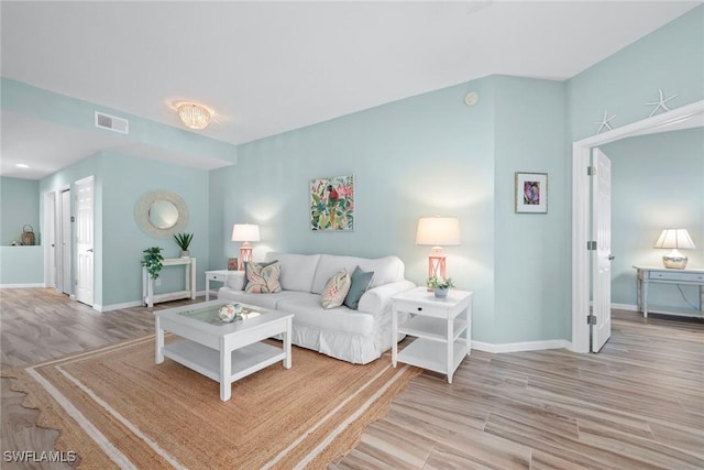 living room featuring visible vents, baseboards, and wood finished floors