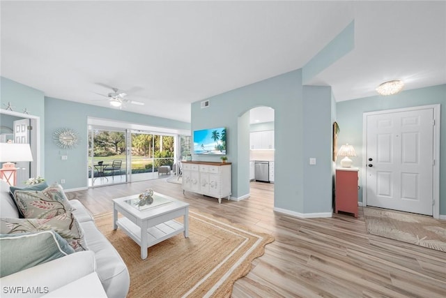 living room featuring arched walkways, visible vents, light wood-style flooring, ceiling fan, and baseboards