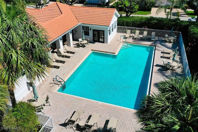 community pool with french doors, a patio area, and fence