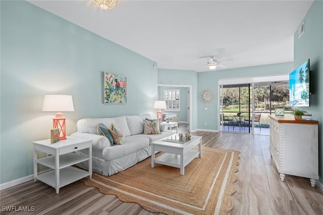 living area with a ceiling fan, wood finished floors, visible vents, and baseboards