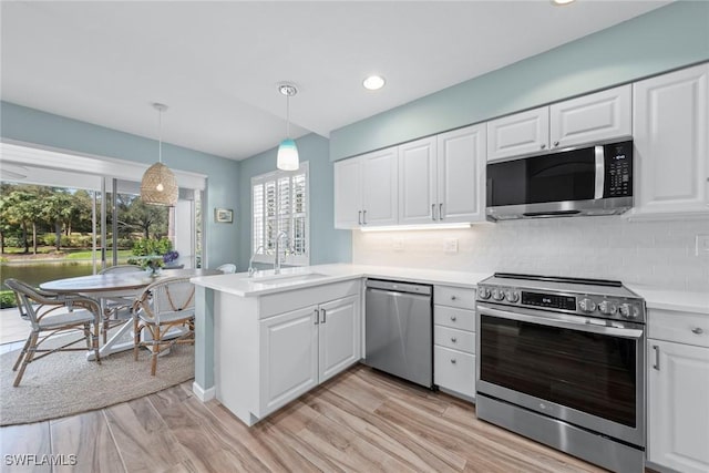 kitchen featuring a peninsula, white cabinetry, appliances with stainless steel finishes, and a sink