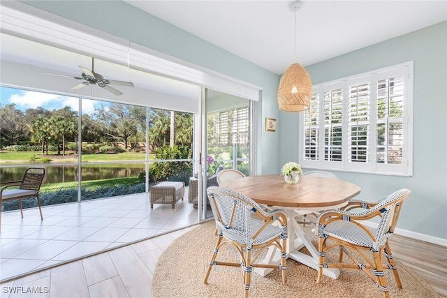 dining area with ceiling fan, a water view, and baseboards