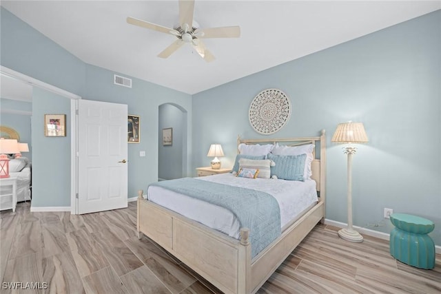 bedroom with baseboards, visible vents, arched walkways, and wood finished floors