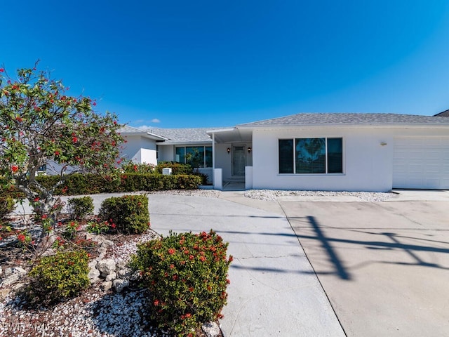 single story home with a garage, driveway, and stucco siding