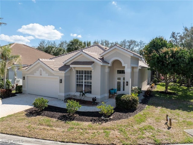 3537 Heron Glen Ct, Bonita Springs, FL 34134 - view of front of home with an attached garage, a tiled roof, french doors, decorative driveway, and stucco siding