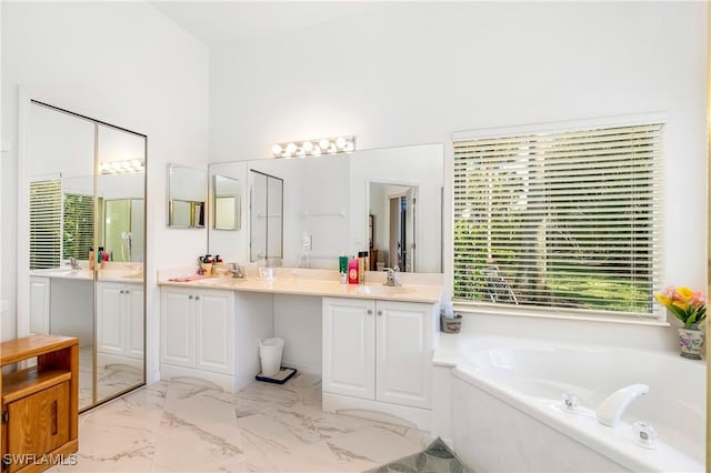 full bathroom featuring marble finish floor, vanity, and a bath