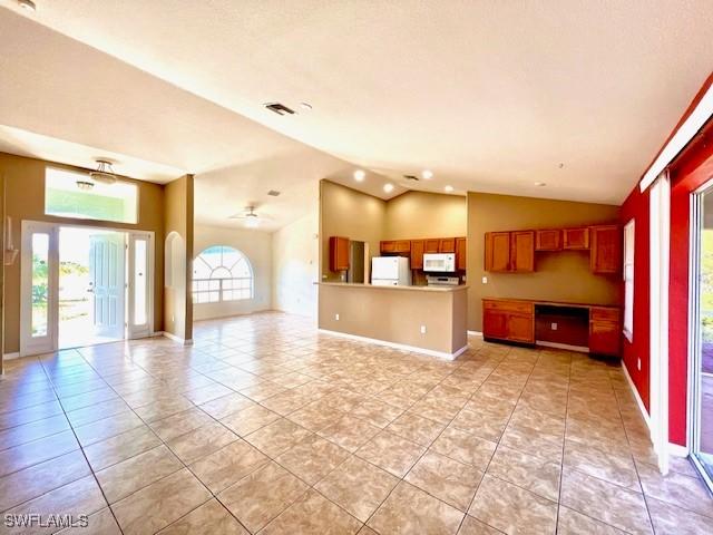 interior space featuring vaulted ceiling, open floor plan, white microwave, and fridge