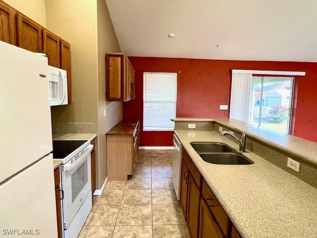 kitchen featuring brown cabinets, white appliances, light countertops, and a sink