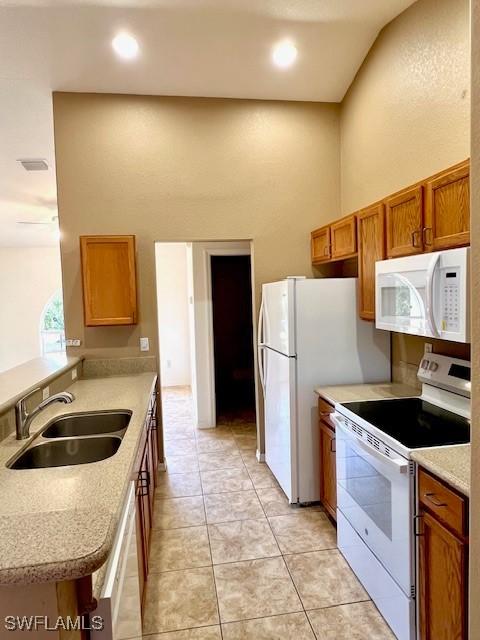 kitchen with white appliances, light countertops, a sink, and brown cabinetry