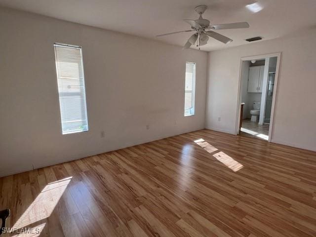 spare room featuring a wealth of natural light, ceiling fan, visible vents, and wood finished floors