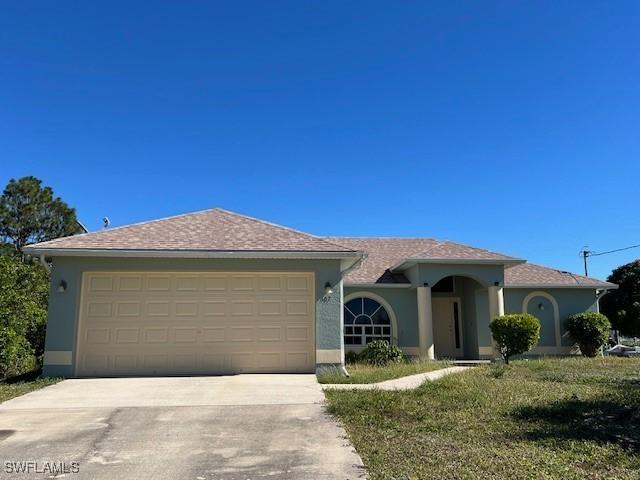 single story home featuring a front yard, concrete driveway, an attached garage, and stucco siding