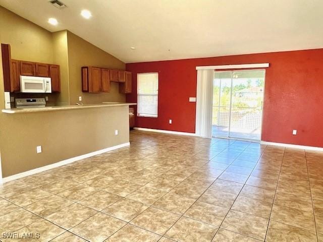 kitchen featuring brown cabinets, lofted ceiling, stainless steel stove, light countertops, and white microwave