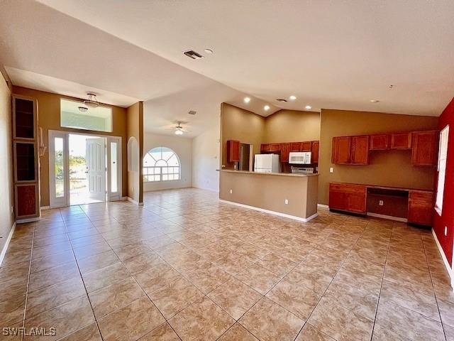 kitchen featuring lofted ceiling, white microwave, refrigerator, open floor plan, and brown cabinetry