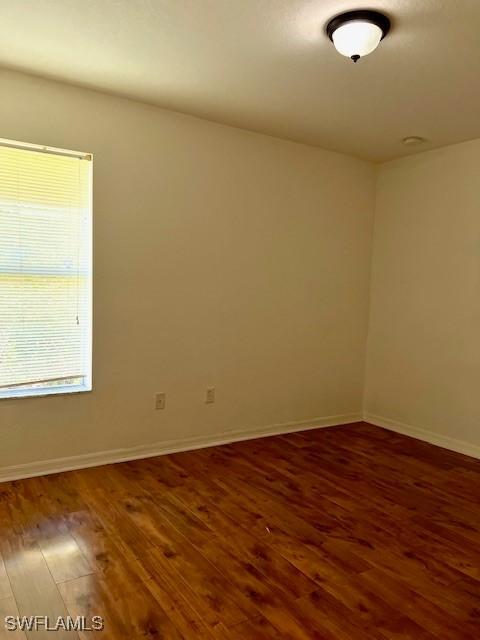 spare room with baseboards and wood finished floors