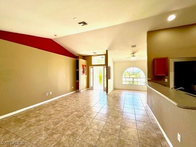 unfurnished living room with light tile patterned floors, visible vents, baseboards, a ceiling fan, and lofted ceiling