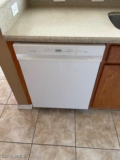 room details with brown cabinetry, light countertops, white dishwasher, and a sink