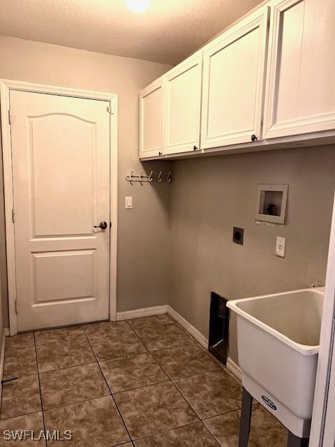 clothes washing area with cabinet space, dark tile patterned flooring, electric dryer hookup, washer hookup, and a sink