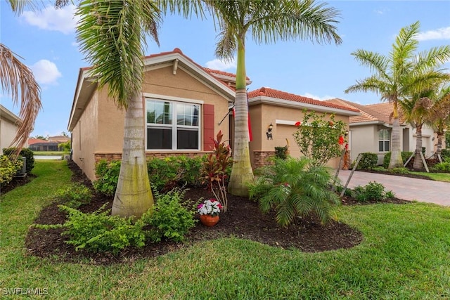 mediterranean / spanish house with a tile roof, a front yard, stucco siding, a garage, and driveway