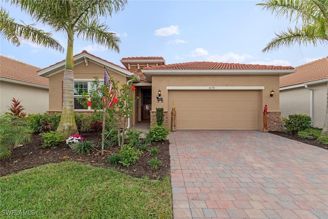 mediterranean / spanish home with a garage, decorative driveway, a tile roof, and stucco siding