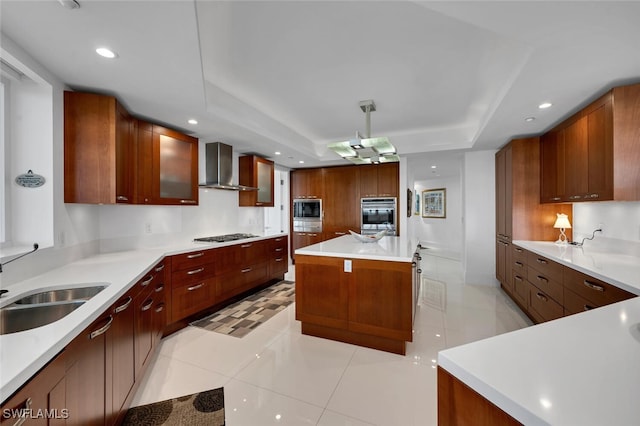 kitchen featuring recessed lighting, a raised ceiling, appliances with stainless steel finishes, a sink, and wall chimney range hood