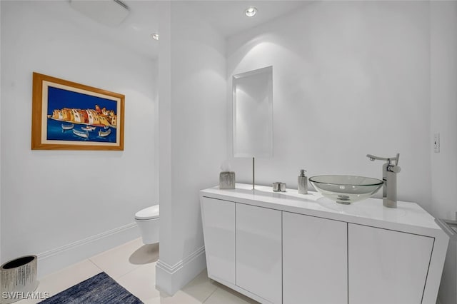 bathroom featuring double vanity, baseboards, toilet, tile patterned floors, and a sink