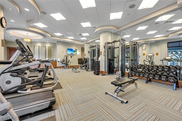 exercise room with a paneled ceiling, carpet, visible vents, and baseboards