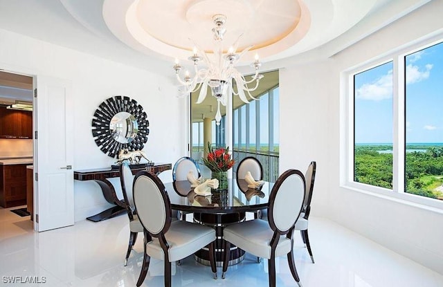 tiled dining area featuring a chandelier and a tray ceiling