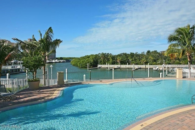 community pool featuring a boat dock, a water view, and fence