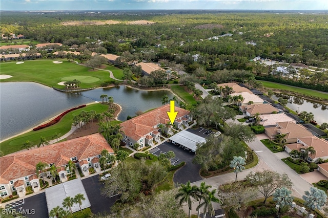 aerial view with view of golf course, a water view, and a view of trees