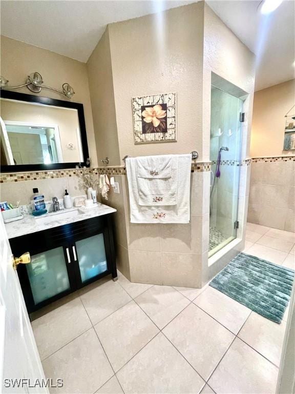 bathroom with a stall shower, tile walls, vanity, and tile patterned floors